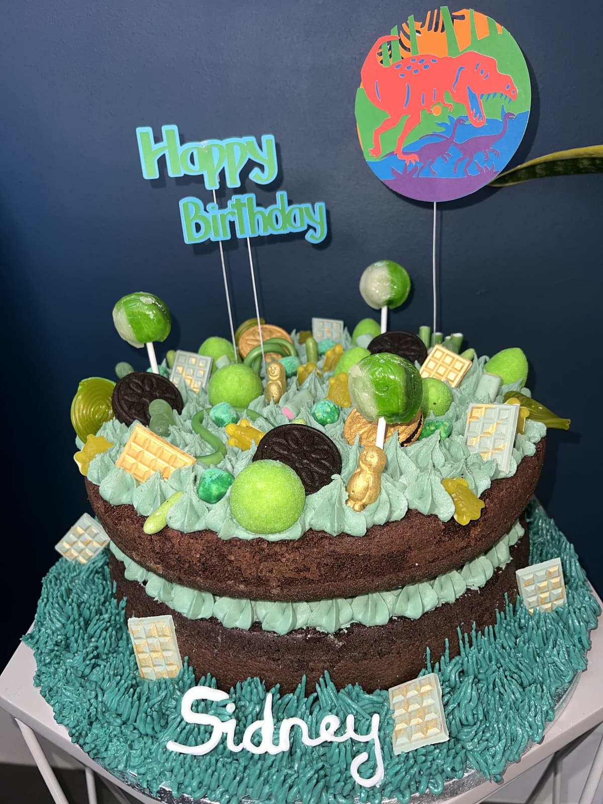 Chocolate naked cake with green buttercream, lollipops and a happy birthday topper