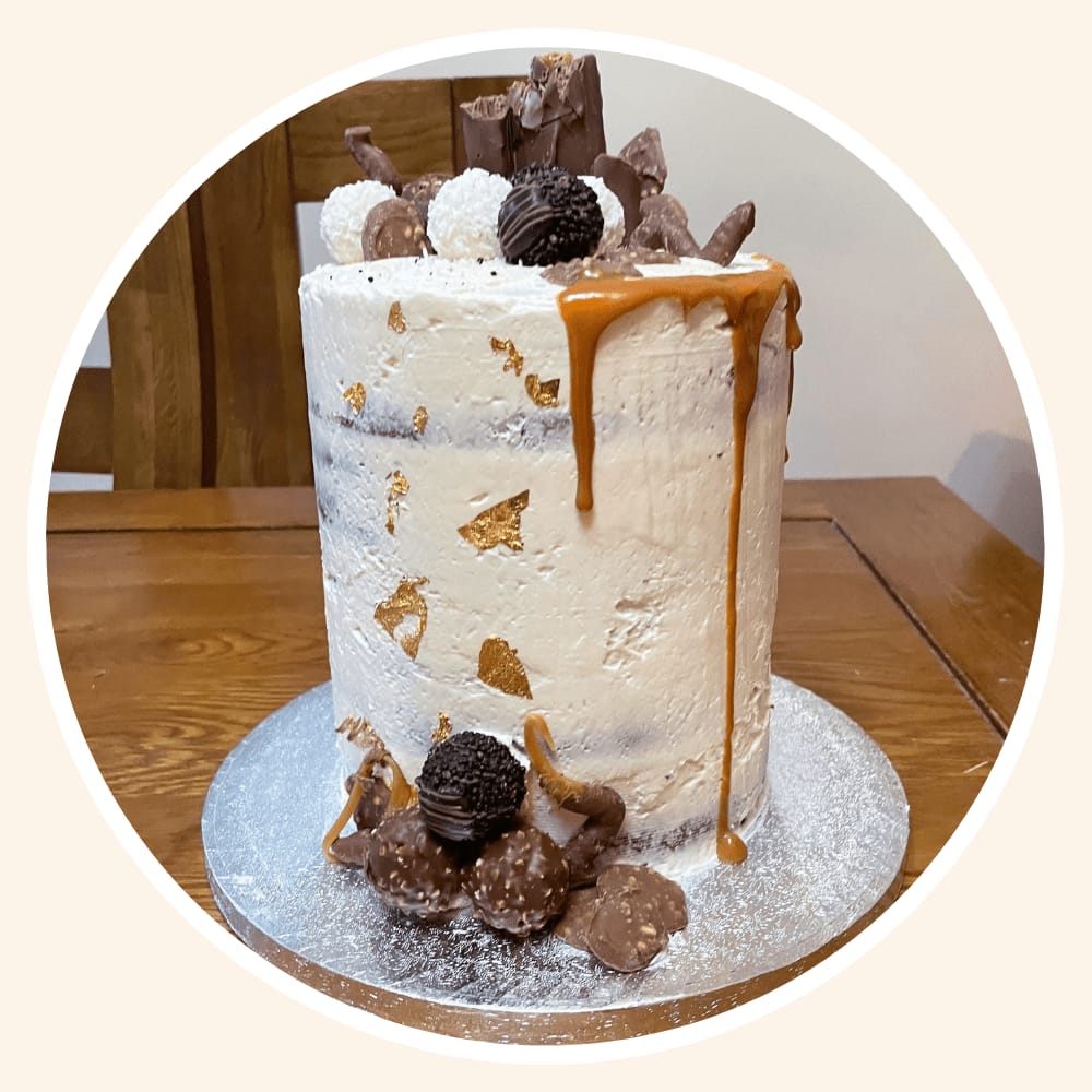 Buttercream cake with gold leaf and a caramel drip, topped with chocolate truffles