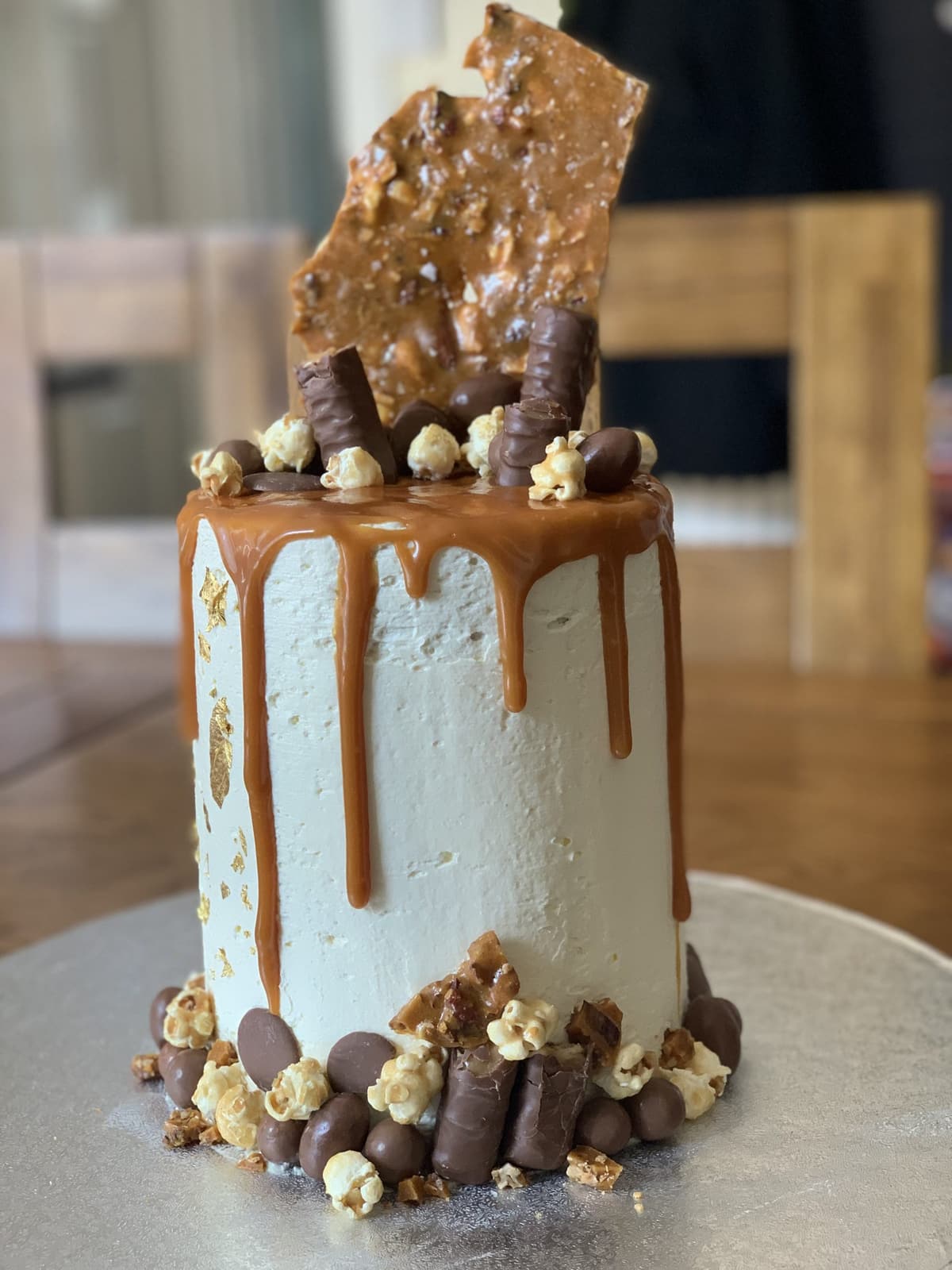 Caramel drip cake topped with a honeycomb shard, popcorn and chocolate truffles