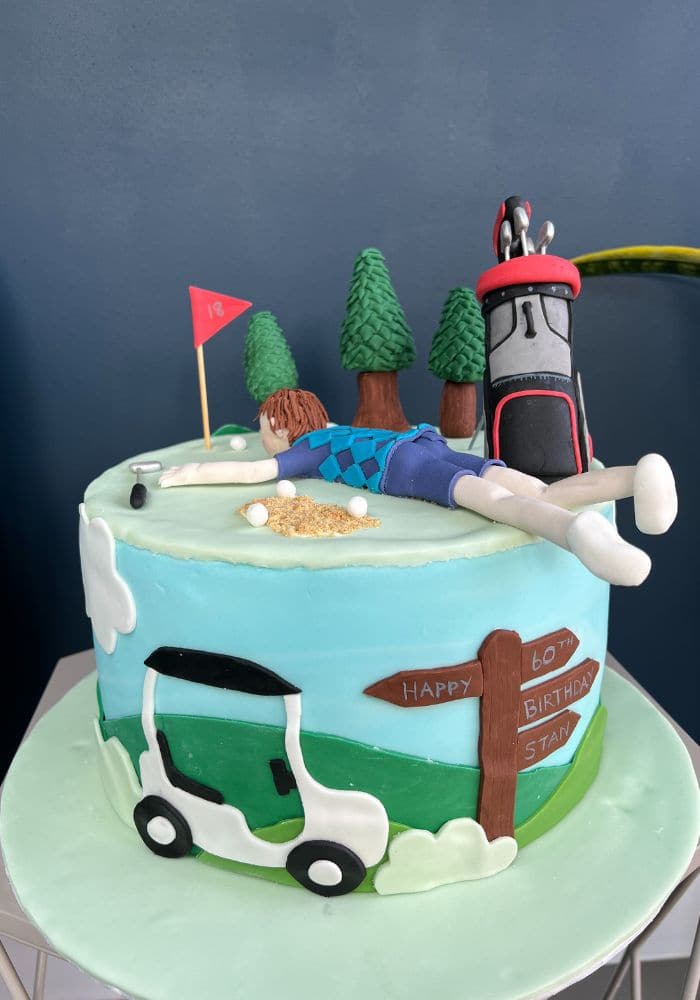 Golf-themed birthday cake with a sugar golfer, trees and a golf bag