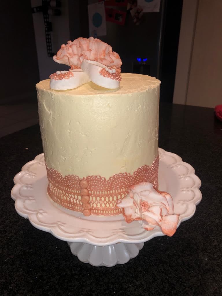 Cream cake with a peach sugar ruffle and lace detail on a pink stand