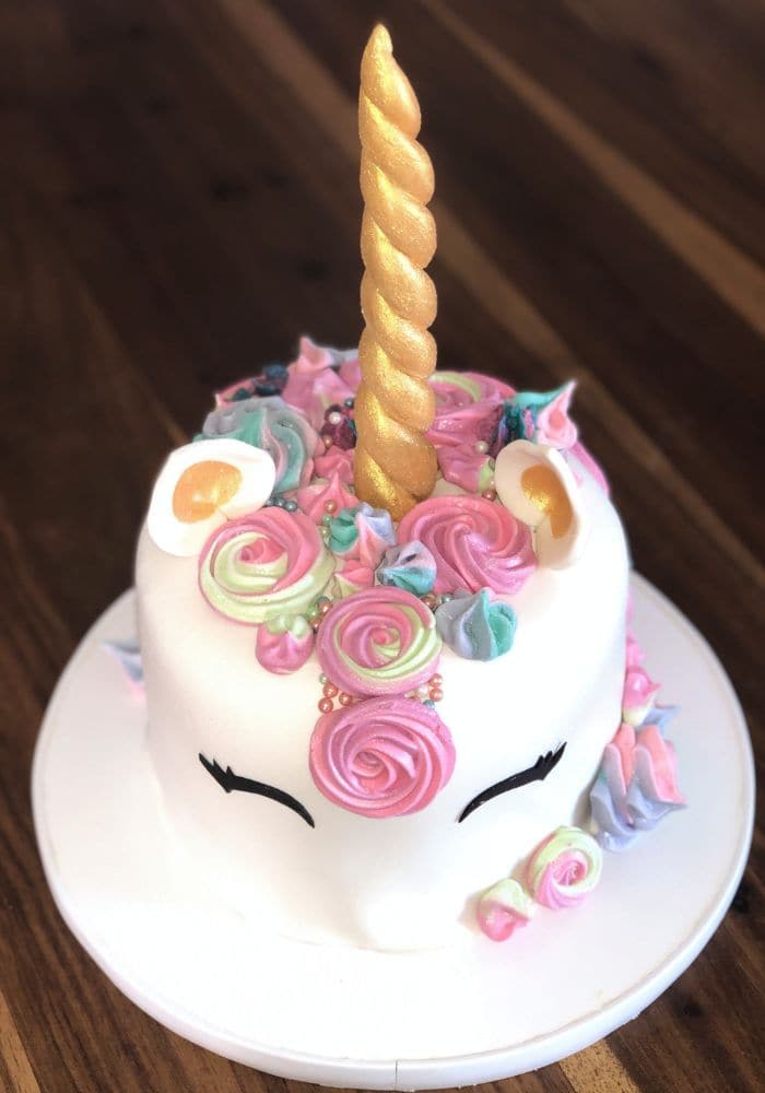 Unicorn cake with pink and blue piped rosettes and a sugar horn