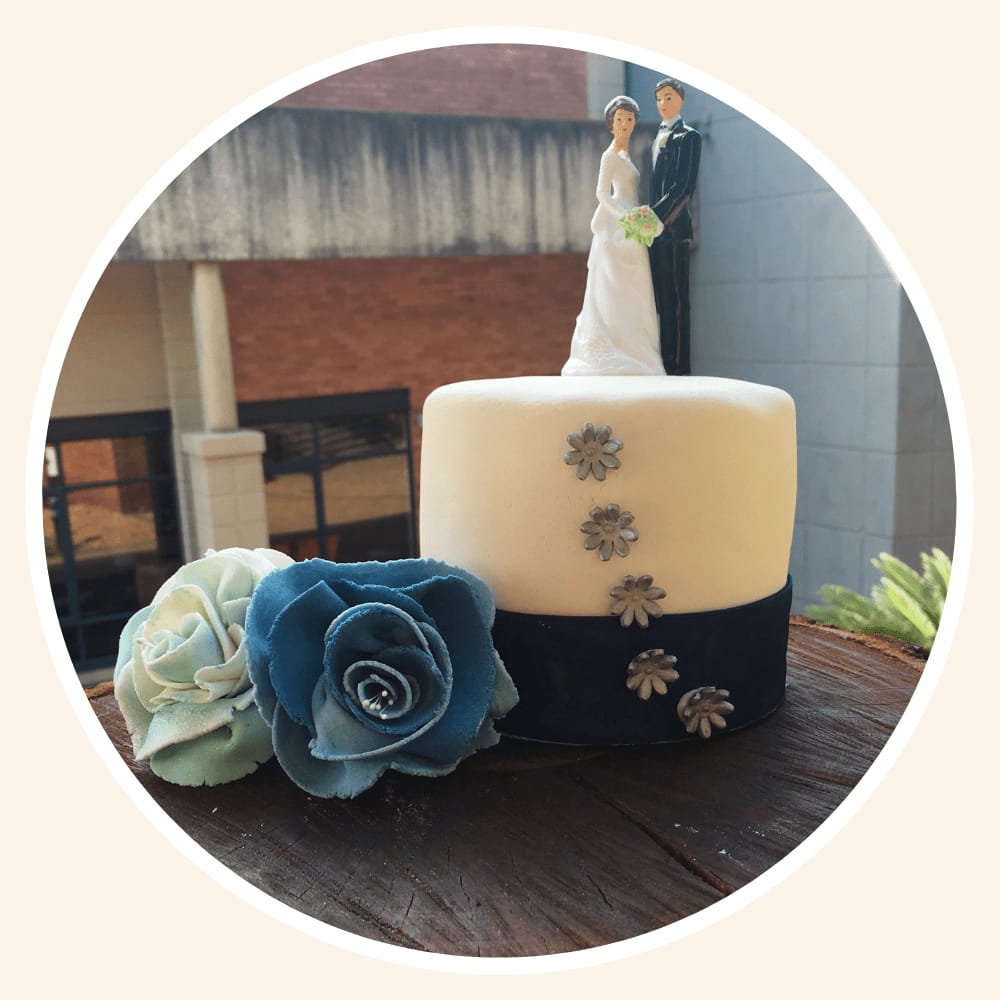 Two-tier wedding cake in navy and cream with sugar flowers and a bride and groom topper