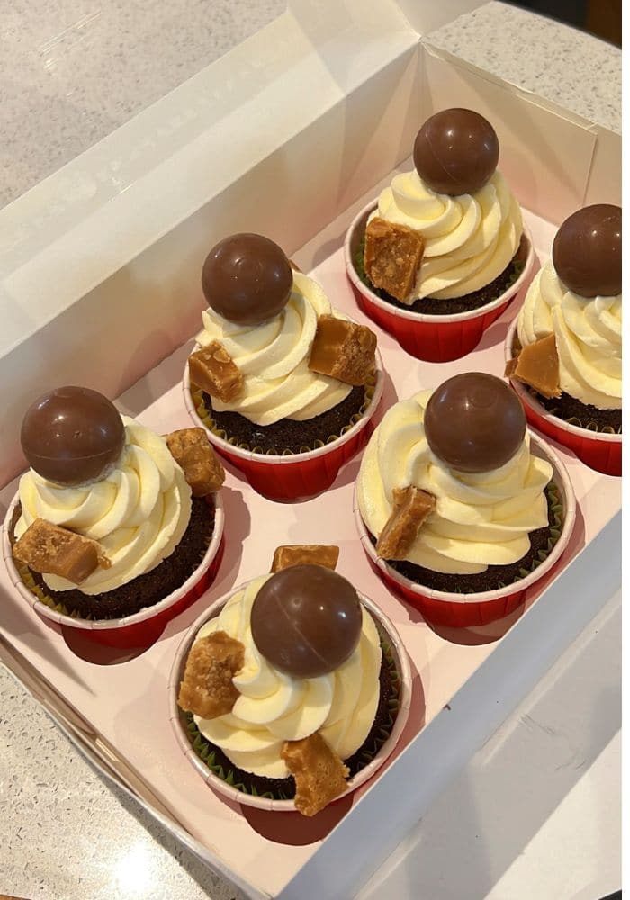 Chocolate cupcakes with a cream swirl, fudge pieces and a chocolate ball