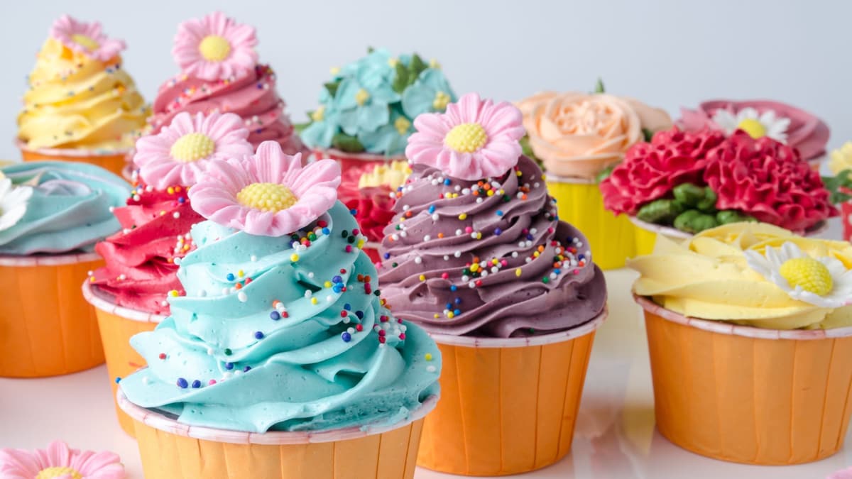 Brightly frosted cupcakes topped with sugar daisies and sprinkles
