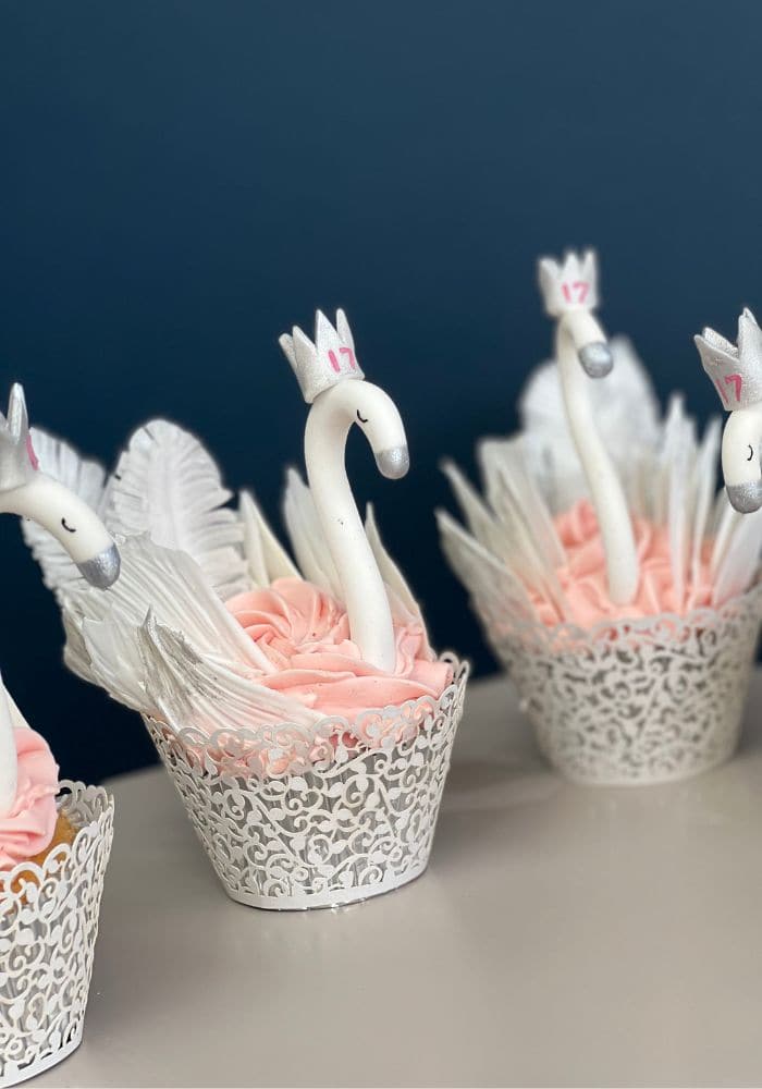 Three cupcakes piped as white swans with feathered wings