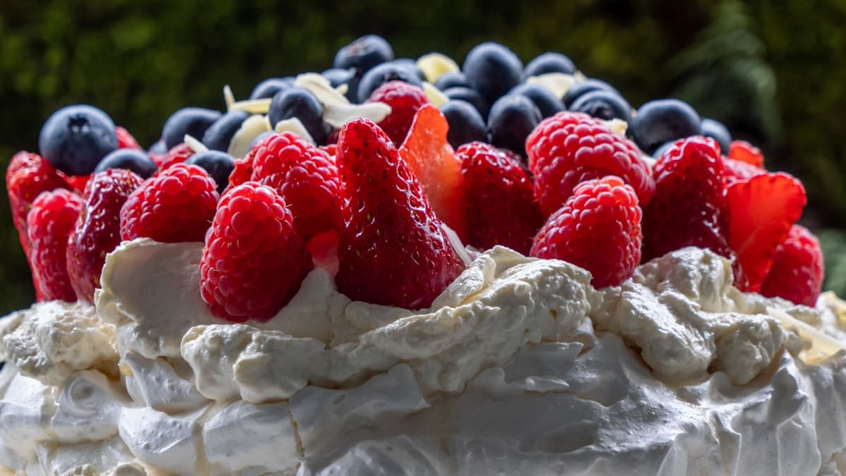 Pavlova piled with fresh strawberries, raspberries and blueberries